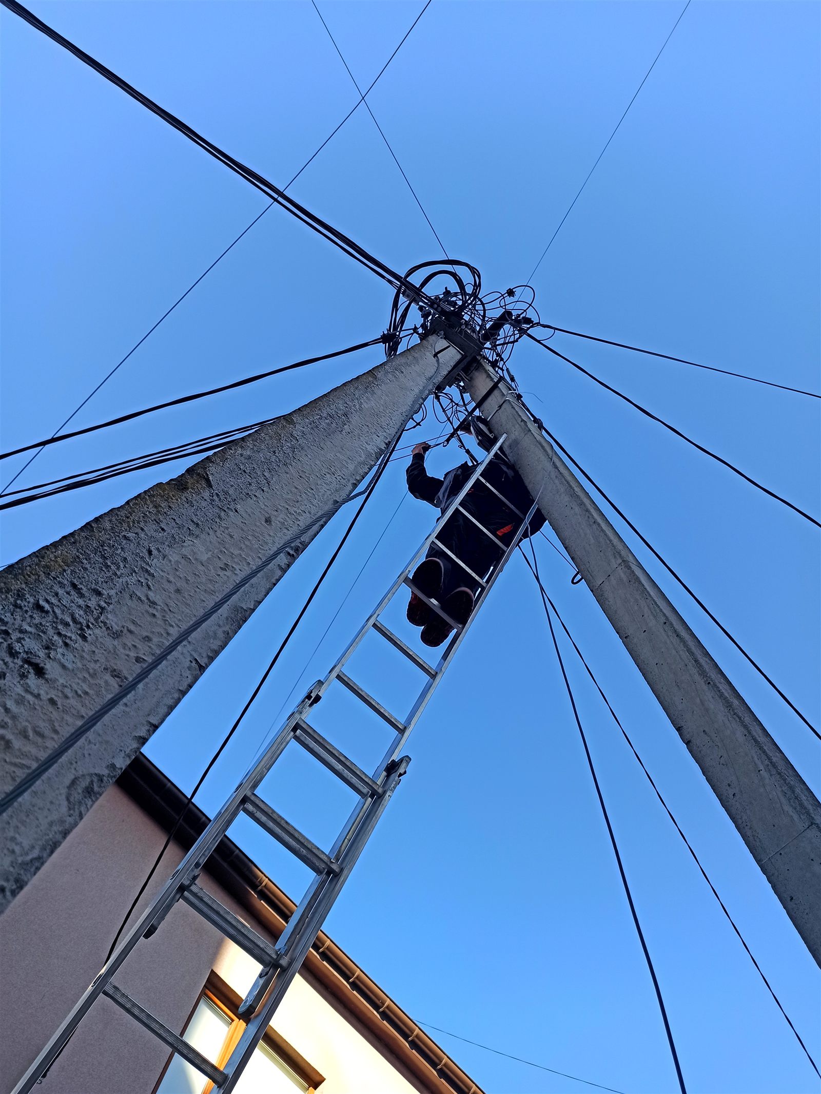 Telecommunications technician installing fibre infrastructure on a utility pole